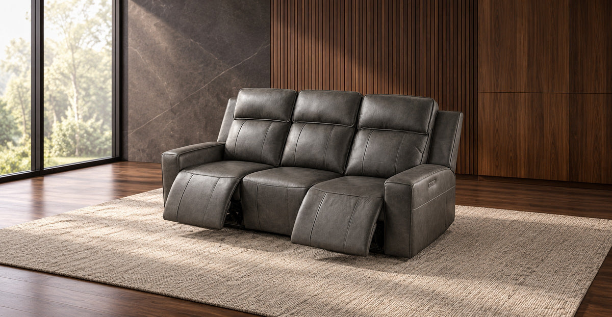 Three-seat dark grey leather recliner sofa with extended footrests in a modern lounge